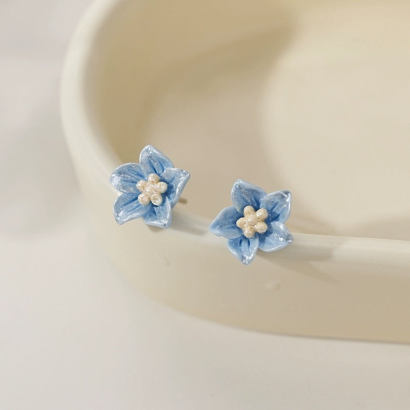 De oorbellen van de blauwe bloemenstudie zijn delicaat en klein