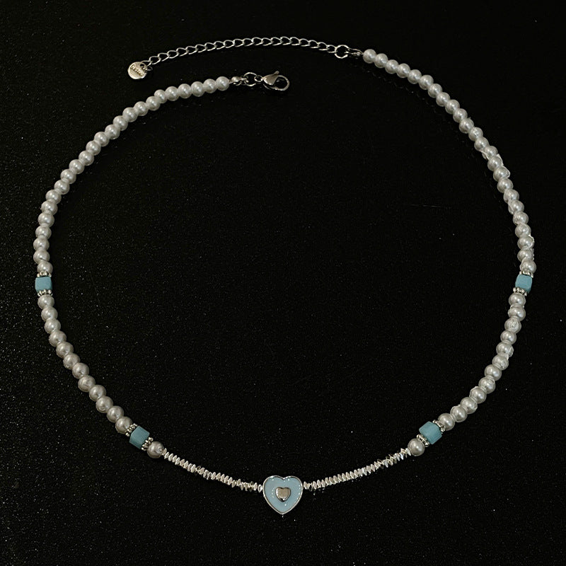 Corazón amante de azul que cose pequeños piezas de collar de perlas de plata