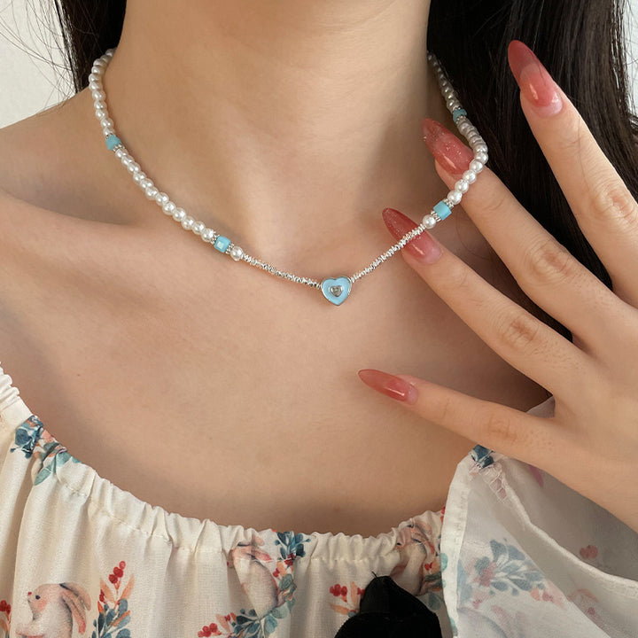 銀の真珠のネックレスの小さな断片を縫う青い愛する心